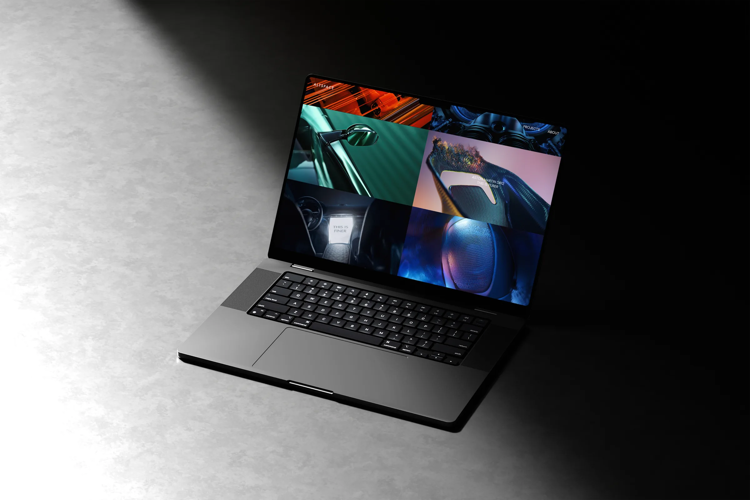 A laptop on a grey floor lit by a single beam, its screen showing a grid of Altspace project stills.