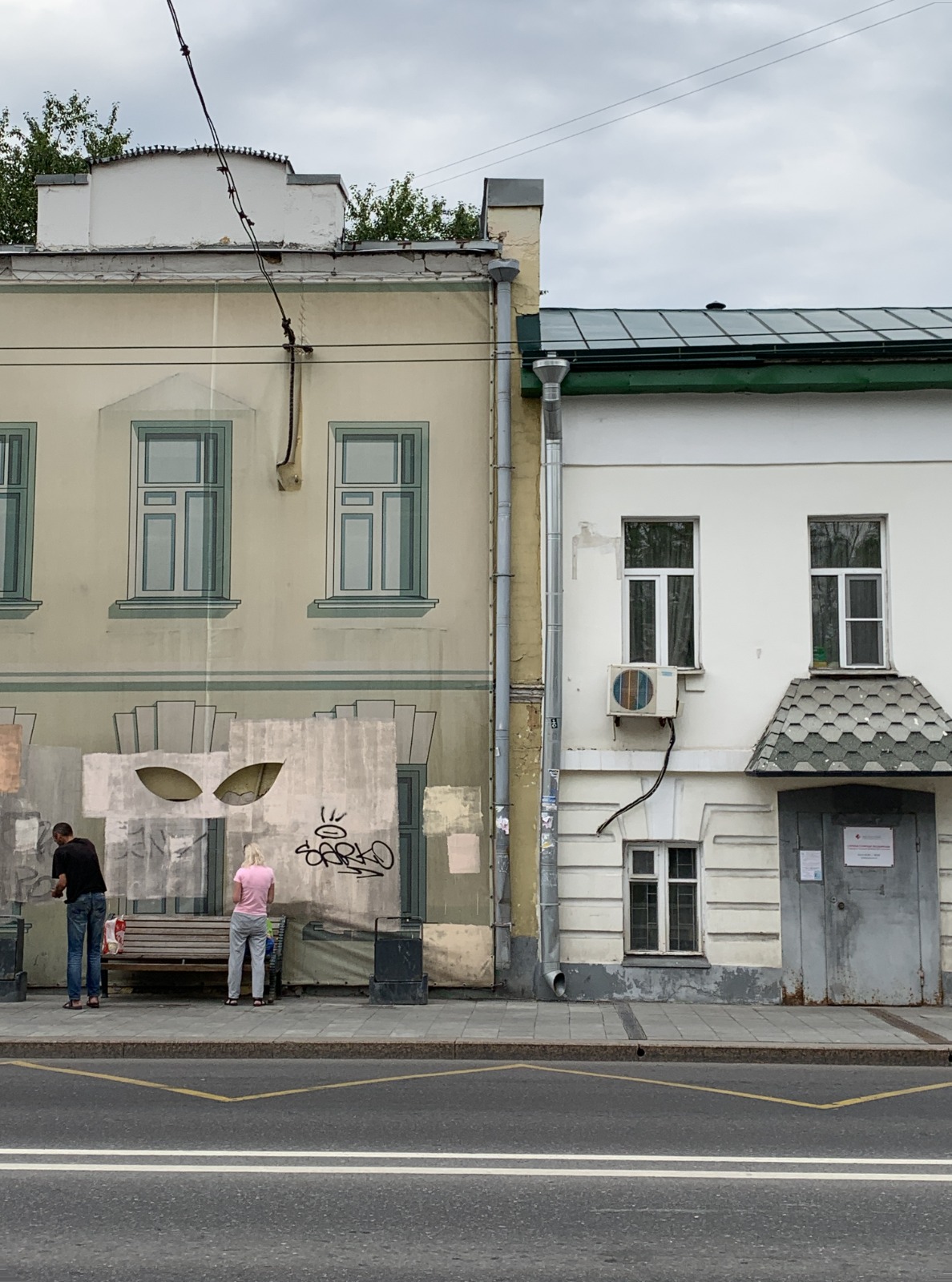 A street façade in Moscow with one of the artist’s pieces pasted over the boarded-up ground floor.